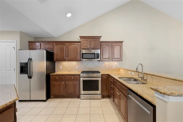 a kitchen with stainless steel appliances granite countertop a stove sink and refrigerator