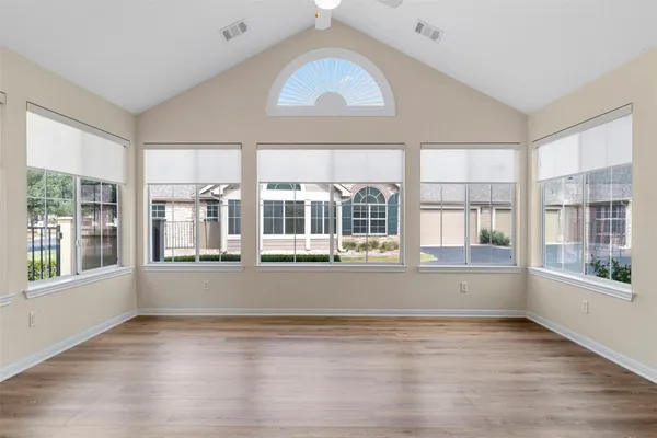 a view of empty room with wooden floor and fan