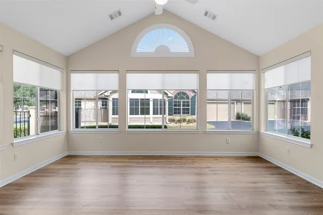 a view of empty room with wooden floor and fan