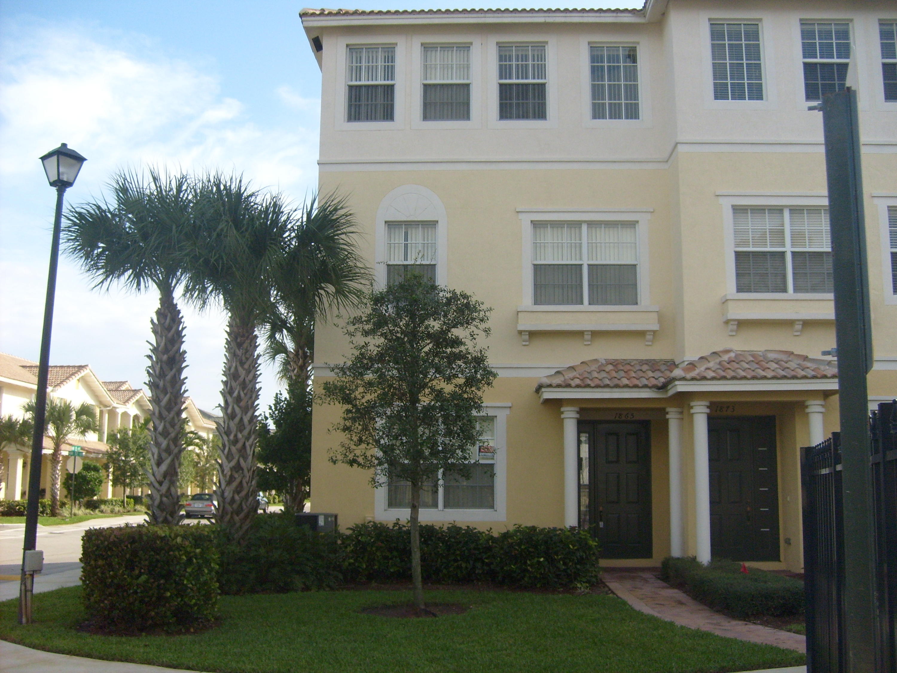 a view of white house with a yard and potted plants
