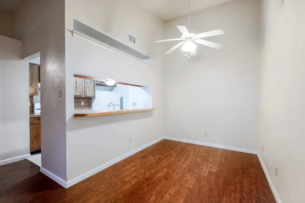 an empty room with wooden floor and fan