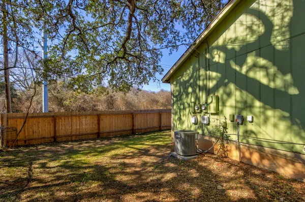 a view of a backyard with large tree and wooden fence