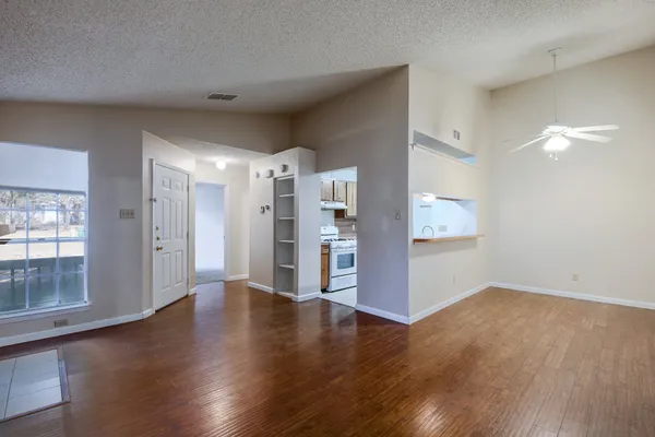 a view of a big room with wooden floor and windows