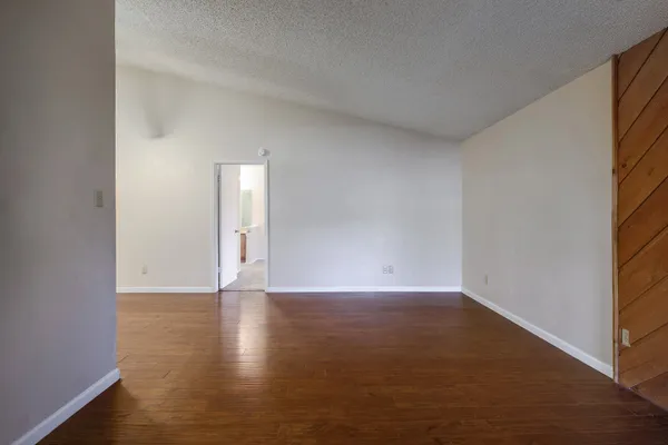 a view of an empty room with wooden floor and a window