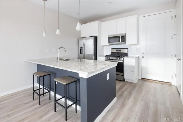 a kitchen with stainless steel appliances granite countertop a kitchen island hardwood floor sink stove and refrigerator