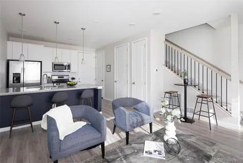 a kitchen with stainless steel appliances kitchen island granite countertop a refrigerator a stove a dining table and chairs with wooden floor