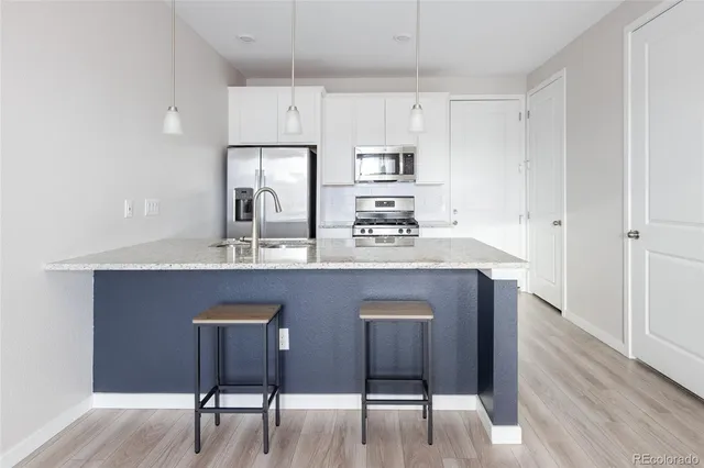a kitchen with stainless steel appliances granite countertop a kitchen island hardwood floor sink stove and white cabinets