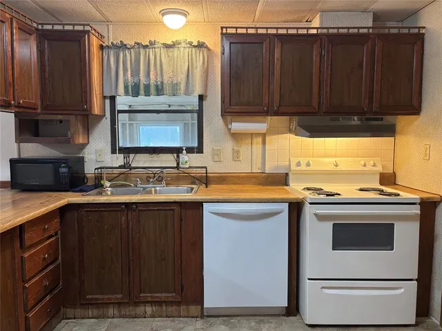 a kitchen with stainless steel appliances granite countertop a stove a sink and a microwave