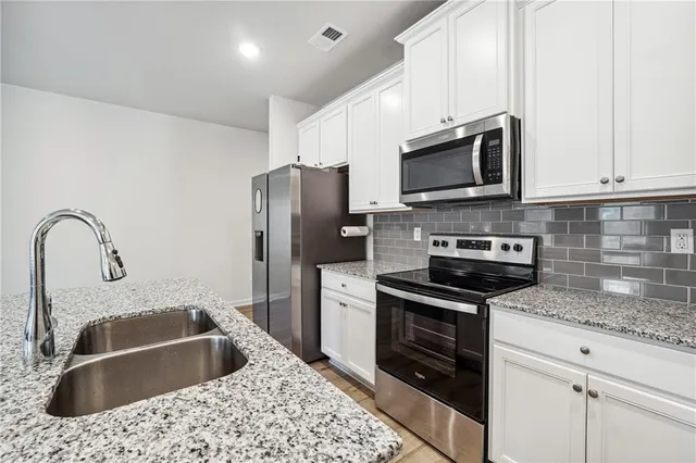 a kitchen with stainless steel appliances granite countertop a sink stove and refrigerator