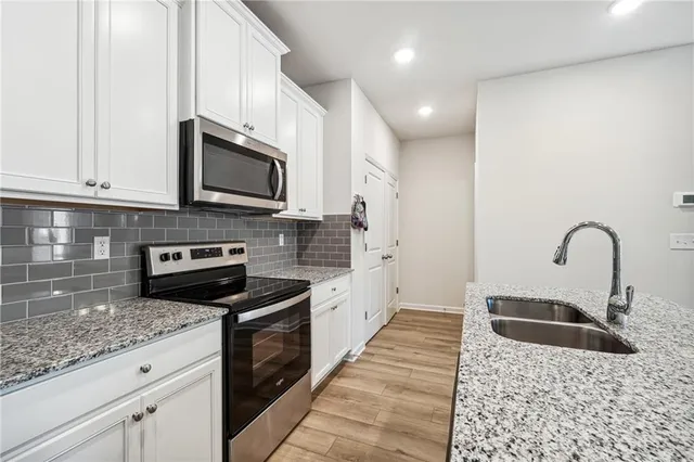 a kitchen with stainless steel appliances granite countertop a sink a stove top oven and granite counter tops