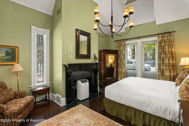 a bedroom with a bed a mirror on dresser and a chandelier