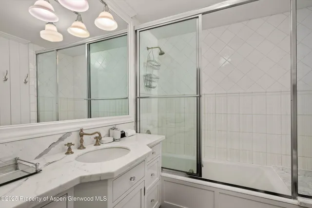 a bathroom with a granite countertop sink a mirror and shower