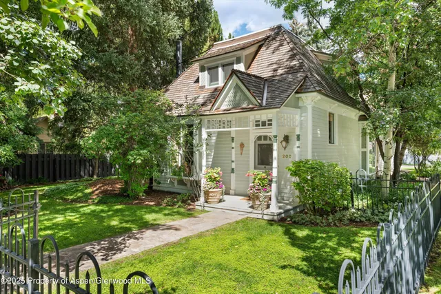 a view of a big house with a big yard plants and large trees