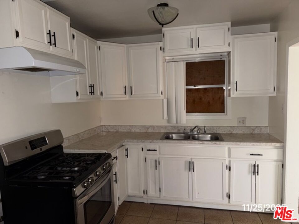 1740 South Rimpau Boulevard Los Angeles, CA 90019 - Photo 14 of 18 a kitchen with granite countertop white cabinets and black stove top oven