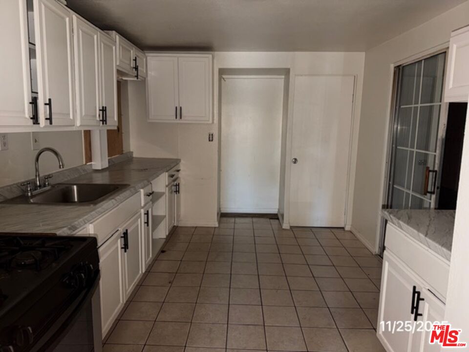 1740 South Rimpau Boulevard Los Angeles, CA 90019 - Photo 9 of 18 a kitchen with granite countertop a sink stove and cabinets