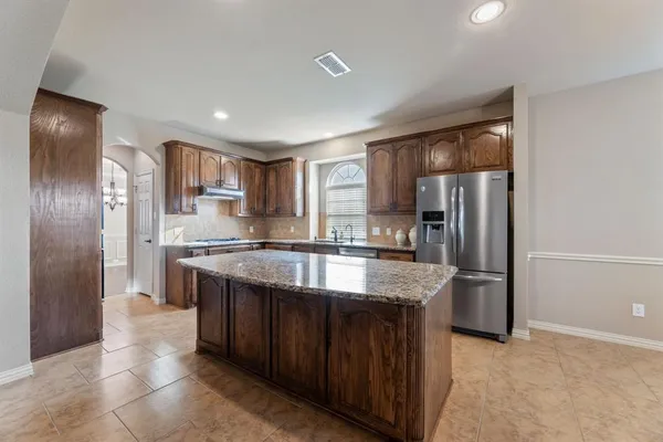 a kitchen with stainless steel appliances granite countertop a refrigerator a sink and a stove