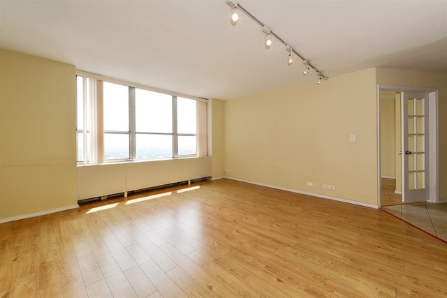 655 West Irving Park Road, Unit 5311 Chicago, IL 60613 - Photo 2 of 10 an empty room with wooden floor and windows