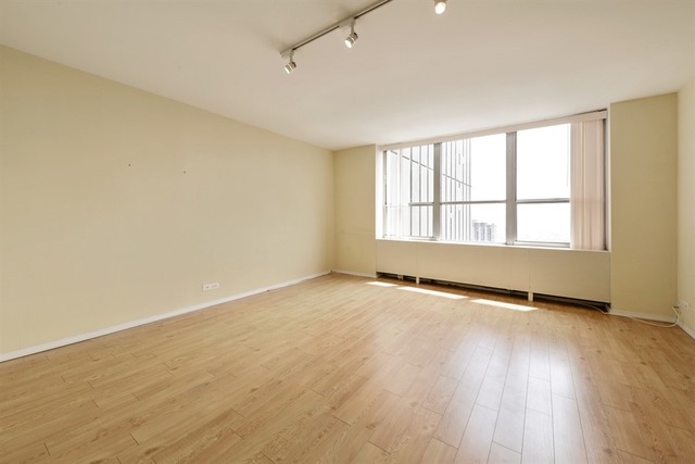 655 West Irving Park Road, Unit 5311 Chicago, IL 60613 - Photo 4 of 10 an empty room with wooden floor and windows