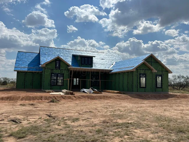 a front view of house with yard and trees in the background