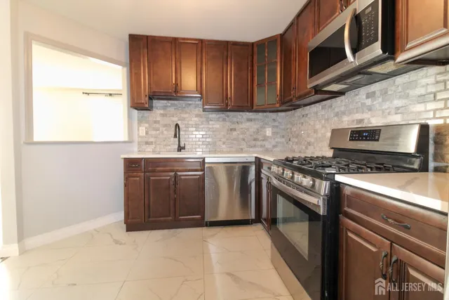 a kitchen with stainless steel appliances granite countertop a stove a sink and a microwave