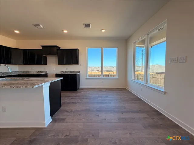 a large kitchen with stainless steel appliances granite countertop a stove a sink and a refrigerator