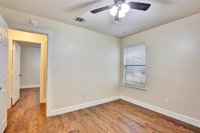 a view of an empty room with a window and wooden floor