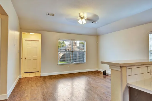 a view of an empty room with a window and wooden floor