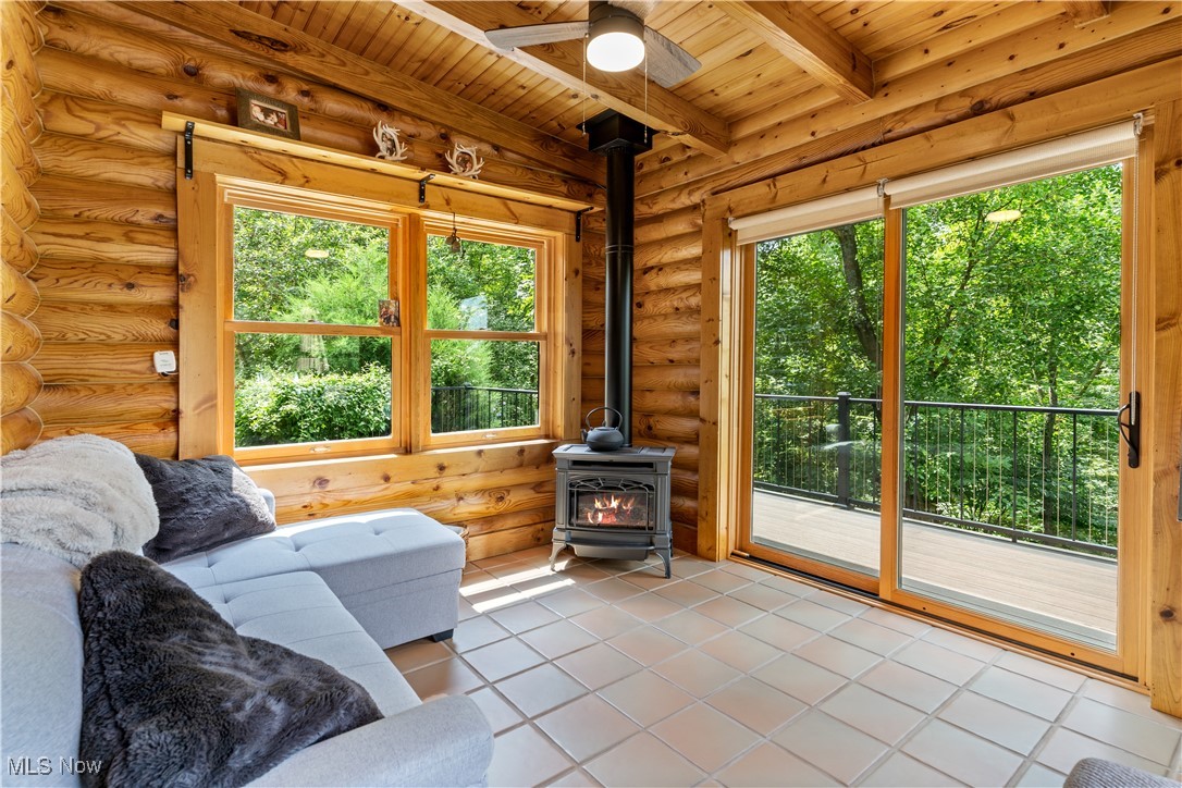 1784 North Medina Line Road Akron, OH 44333 - Photo 11 of 50 Sunroom with a wood stove, beam ceiling, and view of wooded area