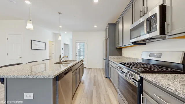 a kitchen with stainless steel appliances granite countertop a sink stove and cabinets