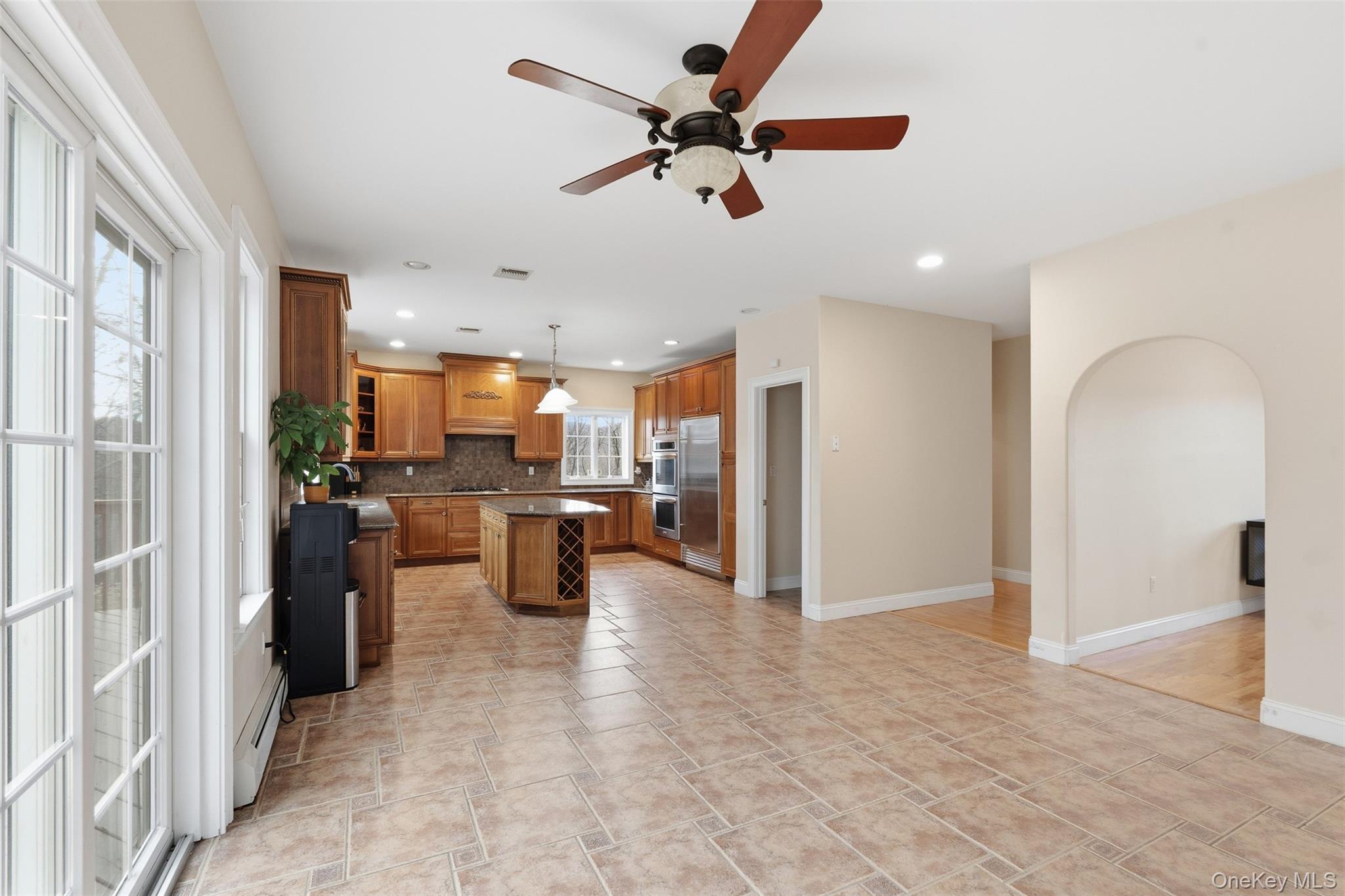 54 Pyngyp Road Stony Point, NY 10980 - Photo 16 of 28 Kitchen with brown cabinets, a kitchen island, decorative backsplash, ceiling fan, and glass insert cabinets