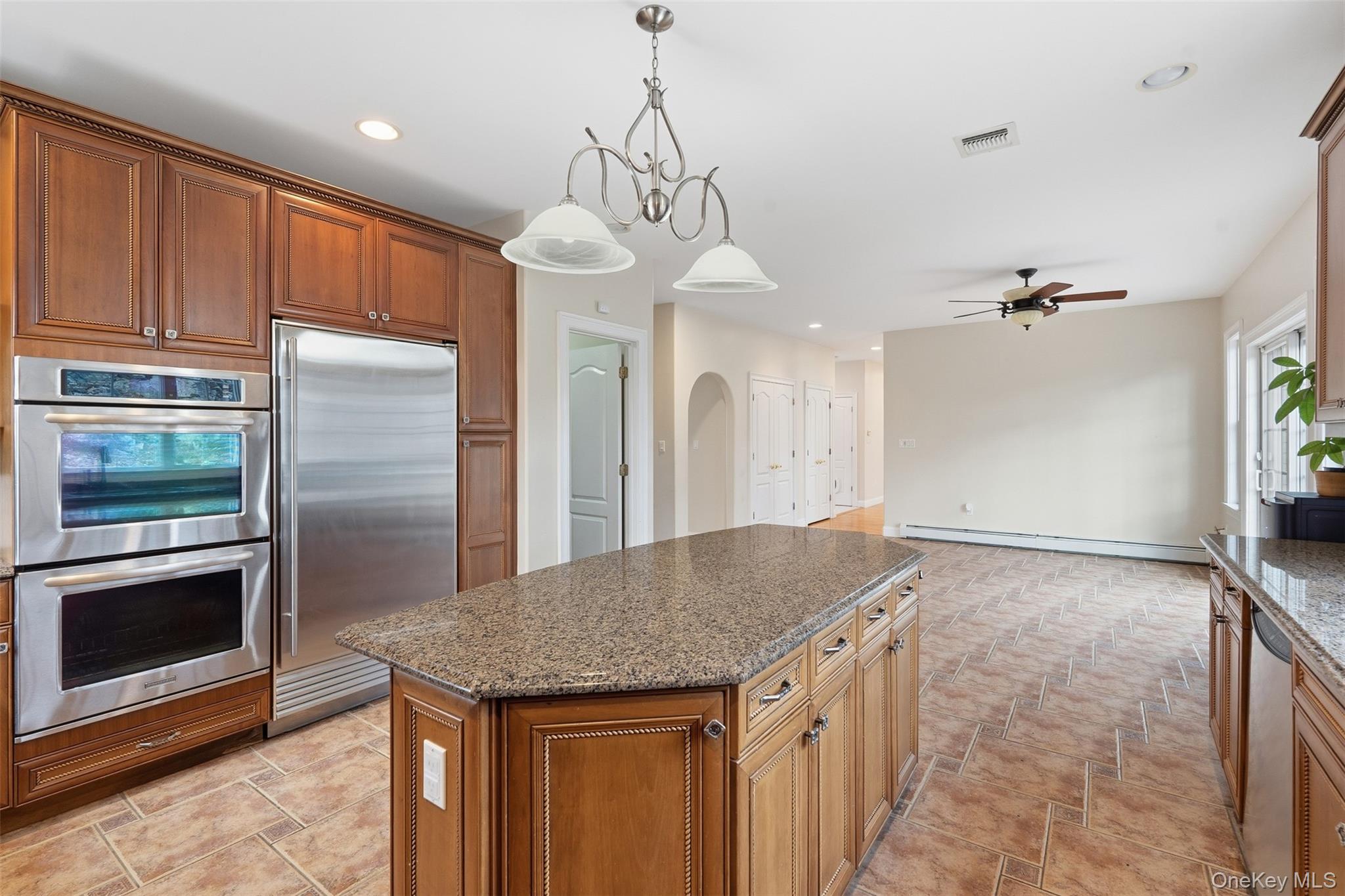 54 Pyngyp Road Stony Point, NY 10980 - Photo 17 of 28 Kitchen featuring dark stone counters, brown cabinetry, appliances with stainless steel finishes, a kitchen island, and recessed lighting