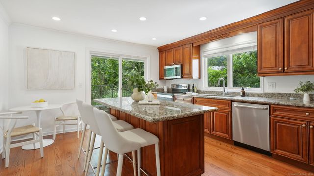a kitchen with stainless steel appliances granite countertop wooden floor a sink a stove and a refrigerator