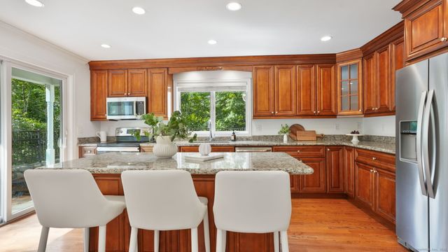 a kitchen with stainless steel appliances granite countertop a stove a refrigerator a sink dishwasher with a dining table and chairs