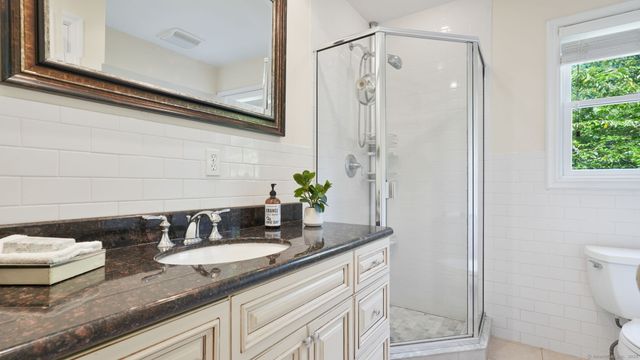 a bathroom with a granite countertop sink a toilet and shower