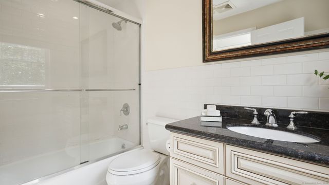 a bathroom with a granite countertop sink a toilet and shower