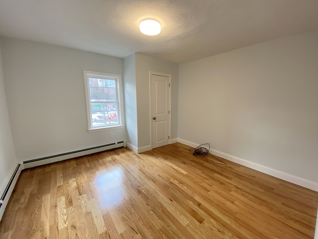 7 Sumner Place, Unit 1 Boston, MA 02128 - Photo 3 of 8 an empty room with wooden floor and windows