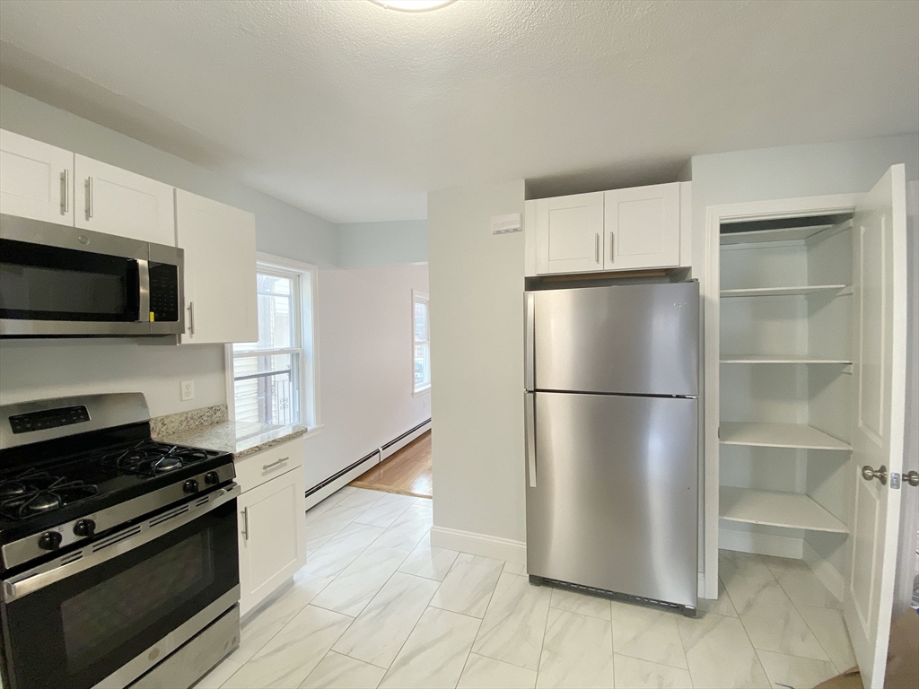 7 Sumner Place, Unit 1 Boston, MA 02128 - Photo 5 of 8 a kitchen with stainless steel appliances a refrigerator stove and microwave