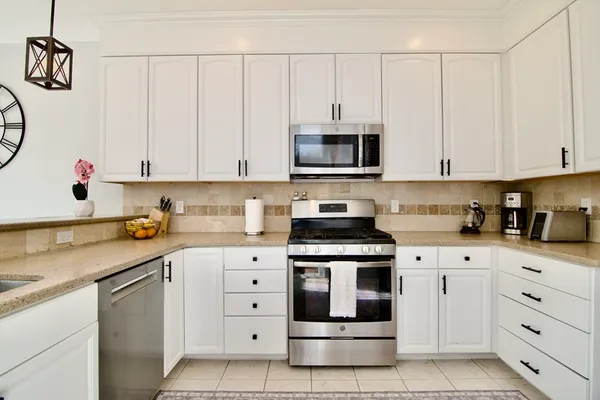 a kitchen with white cabinets and appliances