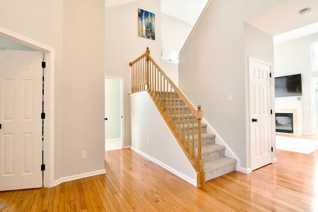 a view of a hallway with wooden floor staircase and living room