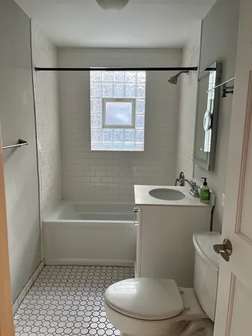 a bathroom with a sink a toilet a mirror a vanity and bathtub