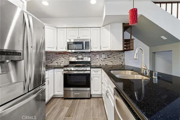 a kitchen with stainless steel appliances granite countertop a stove a sink and a microwave