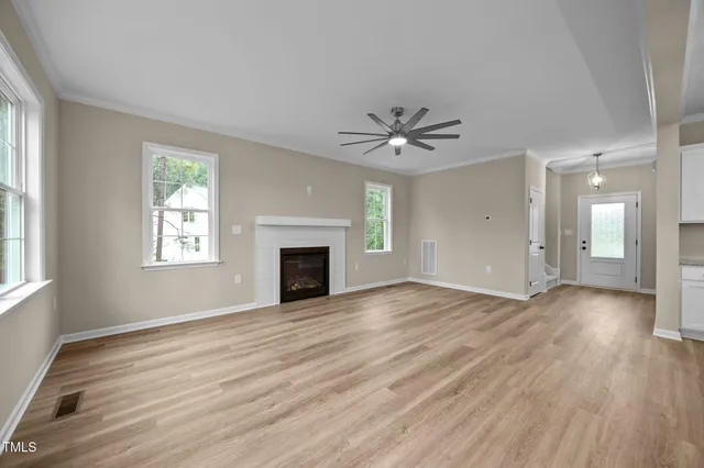 an empty room with wooden floor chandelier and windows