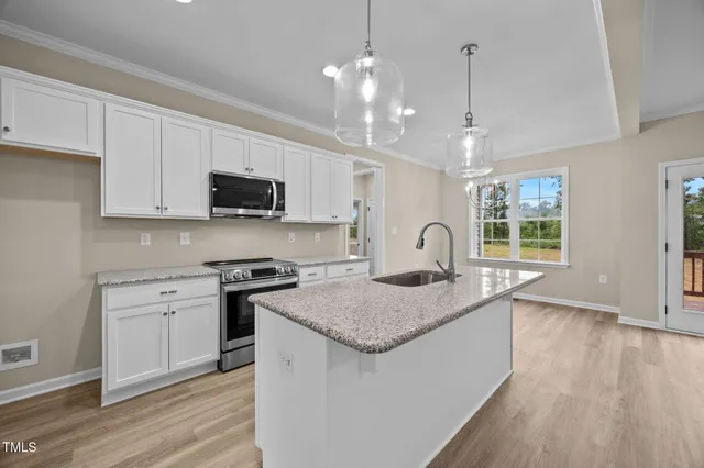 a kitchen with granite countertop a stove a sink a center island and wooden floor