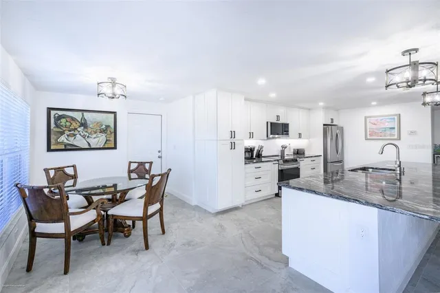 a large white kitchen with a white countertops a stove a couch and a window