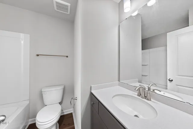 a bathroom with a toilet sink vanity and mirror