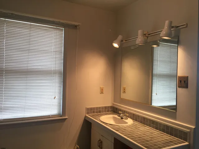 a bathroom with a granite countertop sink and a window