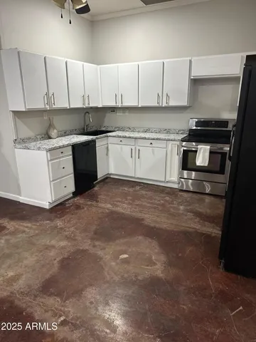 a kitchen with stainless steel appliances granite countertop a stove a sink and white cabinets