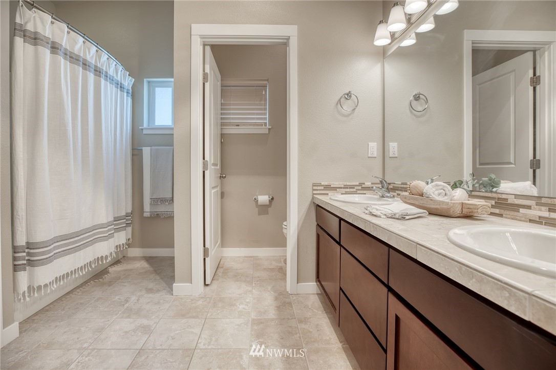 946 North 96th Street Seattle, WA 98103 - Photo 22 of 24 a spacious bathroom with a granite countertop sink a mirror and a shower