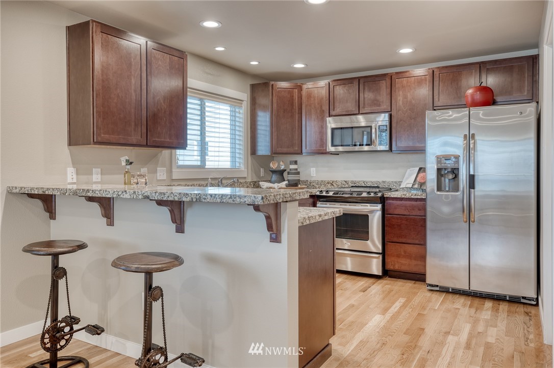 946 North 96th Street Seattle, WA 98103 - Photo 10 of 24 a kitchen with kitchen island granite countertop a sink a counter space stainless steel appliances and cabinets