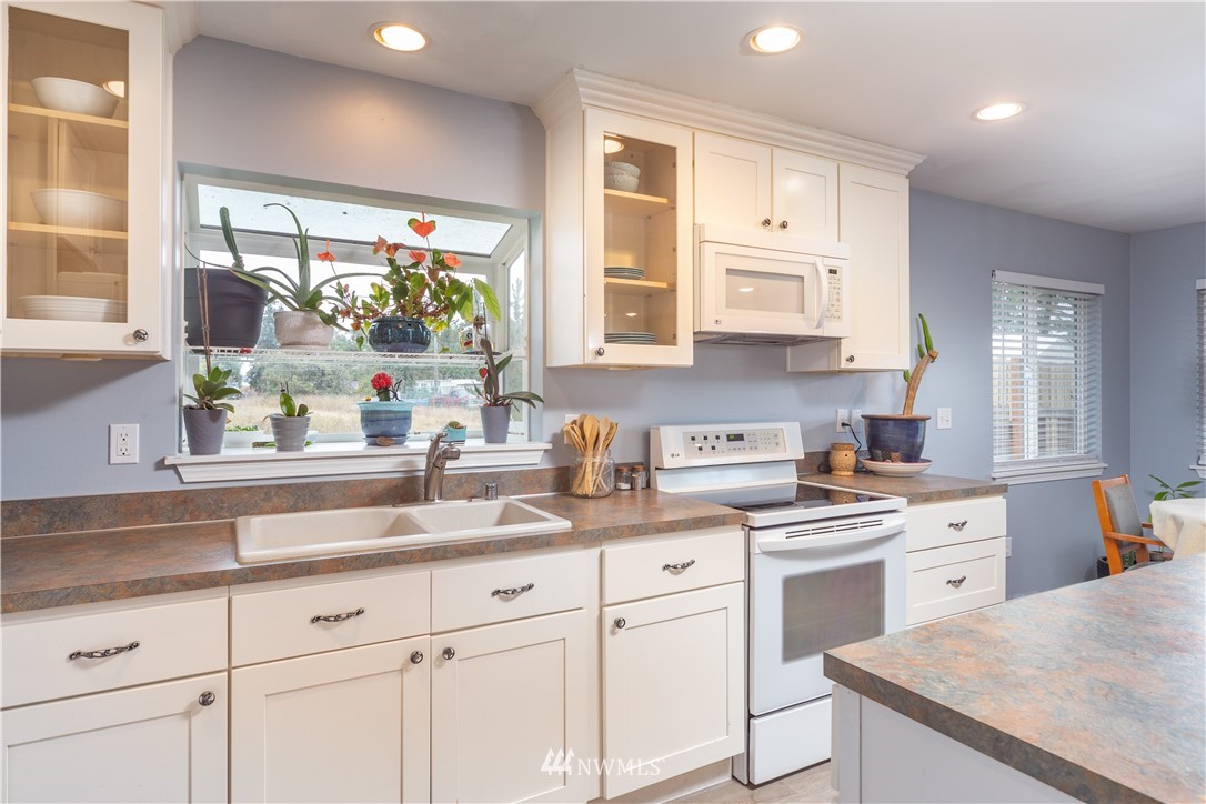 124 Fitzgerald Road Sequim, WA 98382 - Photo 6 of 25 a kitchen with granite countertop white cabinets white appliances and a sink
